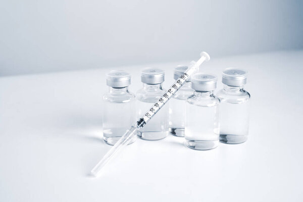 Empty bottle of vaccine with syringe for hygiene injection. Pharmaceutical equipment protective infection of pandemic covid-19 virus, flu, disease. Isolated on white background, copy space.