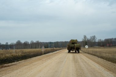 İlkbaharda Letonya kırsalında kar eridiğinde ve çayırlar ıslak kaldığında ve yolda bir traktör saman silindiri taşıdığında