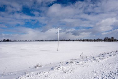 Letonya kırsalında, ortasında kar yağmış bir elektrik direğini görebileceğiniz bir sürü bembeyaz kar manzarası var.