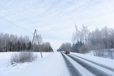 Kışın soğuk günbatımında siyah asfalt donmuş görünüyor.