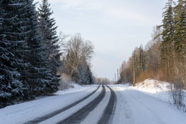 Kışın soğuk günbatımında siyah asfalt donmuş görünüyor.