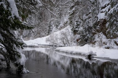 In the middle of the forest is a cliff with a reservoir of water pei those white and fluffy in winter form a reflection in the calm water