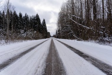 beautiful sunny winter day in Latvia where the asphalt is frozen and there are rails on it where you can see small asphalt stones and snowy