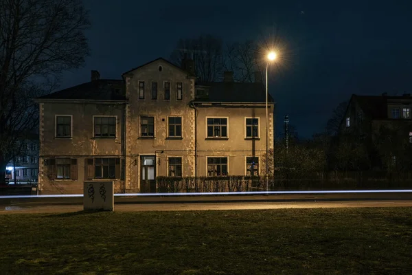 Riga street at night with a house and a lantern that shines on the street