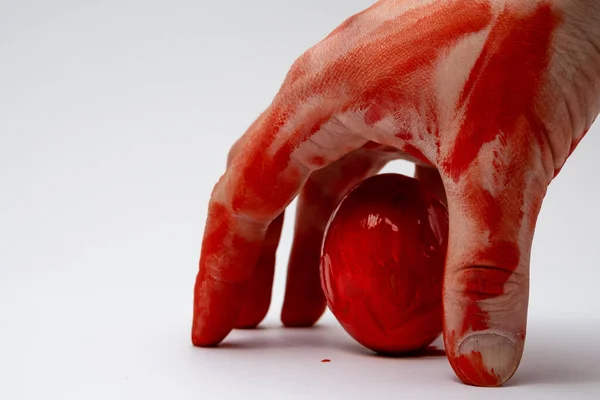 to paint red eggs by hand, the hands are colored red and also on a white background is red