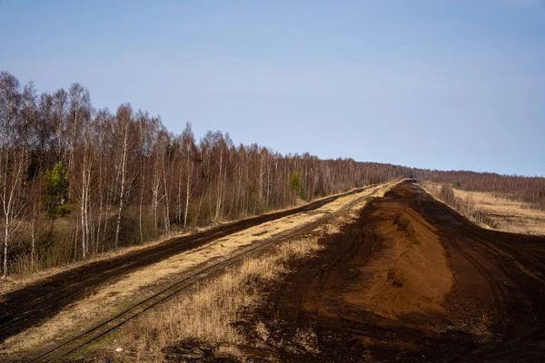 in a peat bog there is a pile of peat along which runs railway tracks at which trees grow