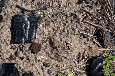 Kamp ateşinden arta kalan kömür siyah ve aralarında kül var.