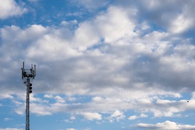 Mavi gökyüzü beyaz bulutlu, yanında büyük bir kutsal kule var.