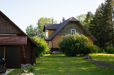 Letonya 'da yaz günü, yeşil çimenli eski bir evi ve garajı olan bir şehir.