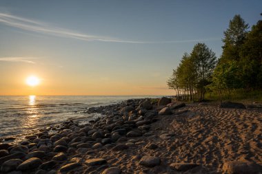 Romantik sıcak gün batımı Baltık Denizi 'nin kayalık sahillerinde