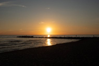 Baltık Denizi 'nin kayalık sahillerinde, küçük dar bir iskelede romantik, ılık bir gün batımı.