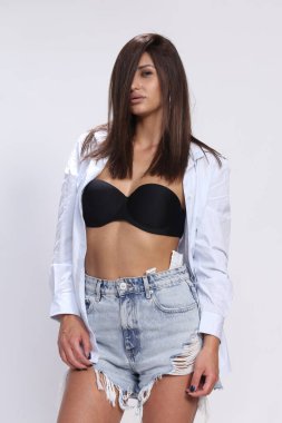 Çekici, kaslı, esmer, beyaz bir kız stüdyoda poz veriyor. Tarz, trendler, moda konsepti.