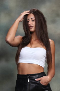 Çekici, kaslı, esmer, beyaz bir kız stüdyoda poz veriyor. Tarz, trendler, moda konsepti.