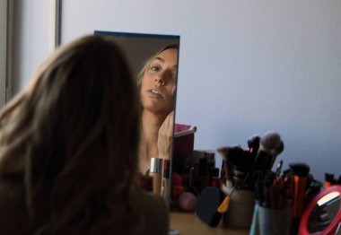 Güzel sarışın kız dairede makyaj yapıyor. Tarz, güzellik, moda konsepti.