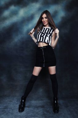 Güzel, pozitif esmer kız stüdyoda tuvalin arka planında poz veriyor. Rahatlama, zarafet, moda konsepti.