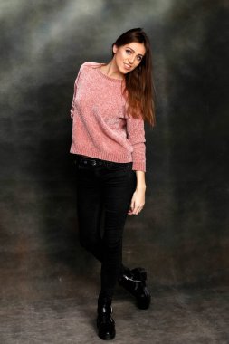 Güzel, pozitif esmer kız stüdyoda tuvalin arka planında poz veriyor. Rahatlama, zarafet, moda konsepti.