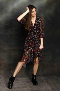 Güzel, pozitif esmer kız stüdyoda tuvalin arka planında poz veriyor. Rahatlama, zarafet, moda konsepti.