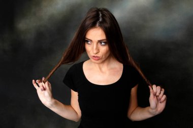 Güzel, pozitif esmer kız stüdyoda tuvalin arka planında poz veriyor. Rahatlama, zarafet, moda konsepti.