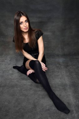 Güzel, pozitif esmer kız stüdyoda tuvalin arka planında poz veriyor. Rahatlama, zarafet, moda konsepti.