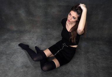 Güzel, pozitif esmer kız stüdyoda tuvalin arka planında poz veriyor. Rahatlama, zarafet, moda konsepti.