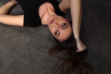 Güzel, pozitif esmer kız stüdyoda tuvalin arka planında poz veriyor. Rahatlama, zarafet, moda konsepti.