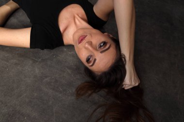 Güzel, pozitif esmer kız stüdyoda tuvalin arka planında poz veriyor. Rahatlama, zarafet, moda konsepti.