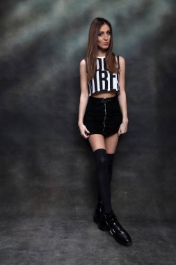 Güzel, pozitif esmer kız stüdyoda tuvalin arka planında poz veriyor. Rahatlama, zarafet, moda konsepti.