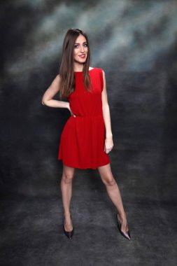 Güzel, pozitif esmer kız stüdyoda tuvalin arka planında poz veriyor. Rahatlama, zarafet, moda konsepti.