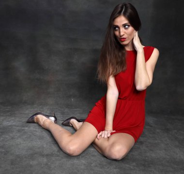 Güzel, pozitif esmer kız stüdyoda tuvalin arka planında poz veriyor. Rahatlama, zarafet, moda konsepti.