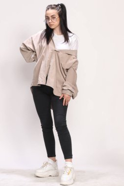 Siyah saçlı, gözlüklü, beyaz tenli güzel bir kız stüdyoda poz veriyor. Tarz, trendler, moda konsepti.