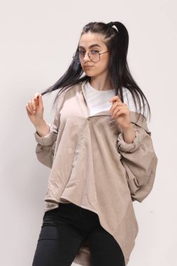 Siyah saçlı, gözlüklü, beyaz tenli güzel bir kız stüdyoda poz veriyor. Tarz, trendler, moda konsepti.
