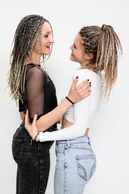 Ayrıştırılmış arka planda afro örgülü iki güzel kız kardeş stüdyoda poz veriyor. Aşk, arkadaşlar, aile ilişkileri.