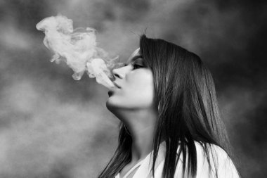 Stüdyoda poz veren ve puro içen çekici esmer kız. Kara film, eski tarz fotoğrafçılık. Cazibe, yaşam tarzı, moda konsepti.