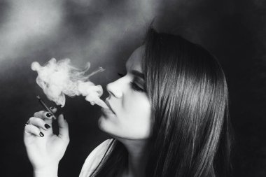 Stüdyoda poz veren ve puro içen çekici esmer kız. Kara film, eski tarz fotoğrafçılık. Cazibe, yaşam tarzı, moda konsepti.