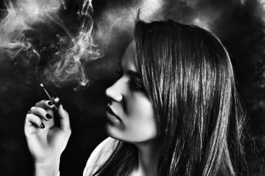 Stüdyoda poz veren ve puro içen çekici esmer kız. Kara film, eski tarz fotoğrafçılık. Cazibe, yaşam tarzı, moda konsepti.