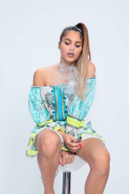 Güzel esmer kadın model stüdyoda poz veriyor ve izole edilmiş arka planda elektrikli puro içiyor. Tarz, sigara, moda konsepti.