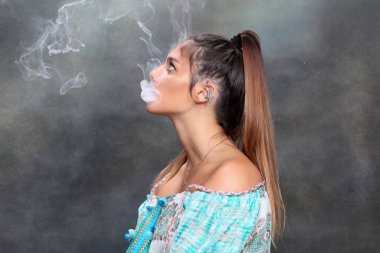 Güzel esmer kadın model stüdyoda poz veriyor ve izole edilmiş arka planda elektrikli puro içiyor. Tarz, sigara, moda konsepti.