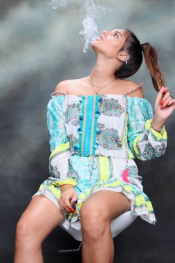 Güzel esmer kadın model stüdyoda poz veriyor ve izole edilmiş arka planda elektrikli puro içiyor. Tarz, sigara, moda konsepti.