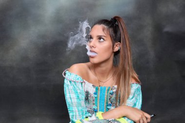 Güzel esmer kadın model stüdyoda poz veriyor ve izole edilmiş arka planda elektrikli puro içiyor. Tarz, sigara, moda konsepti.