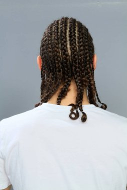 Çekici, kafkasyalı erkek model. Stüdyoda izole edilmiş arka planda saç örgüleri var. Tarz, trendler, moda konsepti.