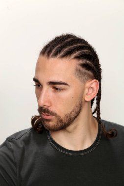 Çekici, kafkasyalı erkek model. Stüdyoda izole edilmiş arka planda saç örgüleri var. Tarz, trendler, moda konsepti.
