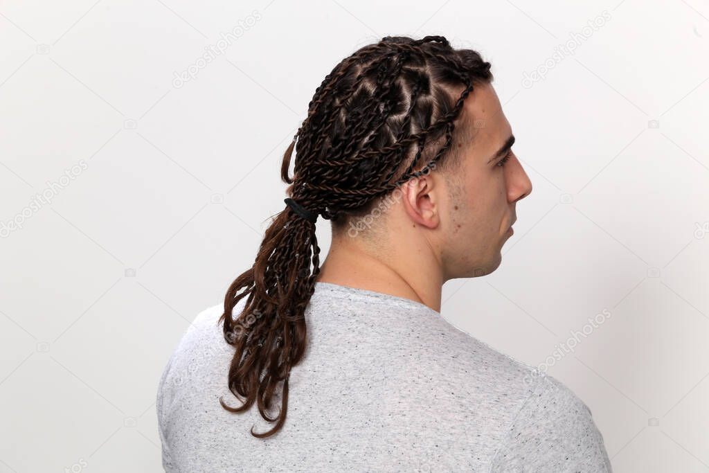 Attractive, caucasian male model with braids posing in studio on isolated background. Style, trends, fashion concept.