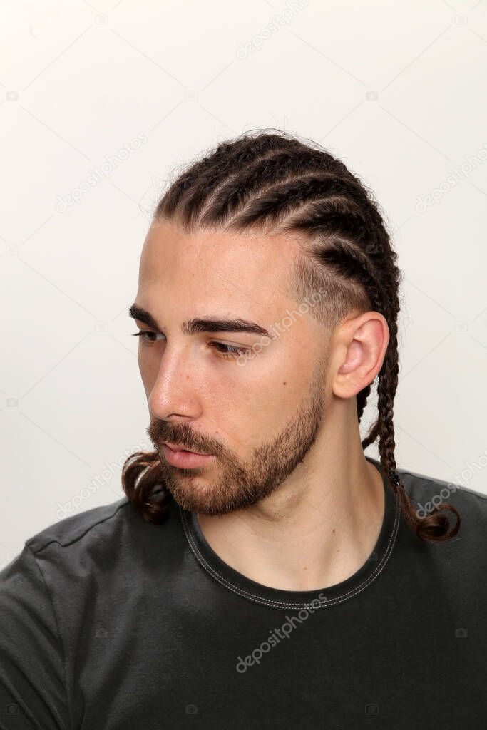 Attractive, caucasian male model with braids posing in studio on isolated background. Style, trends, fashion concept.