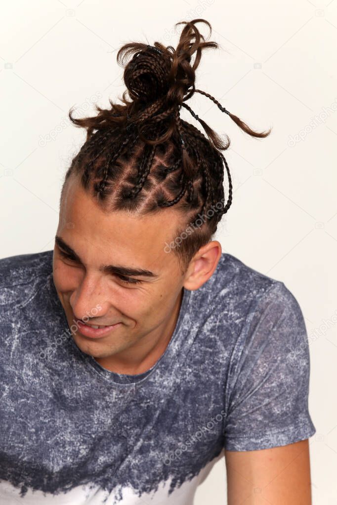 Attractive, caucasian male model with braids posing in studio on isolated background. Style, trends, fashion concept.