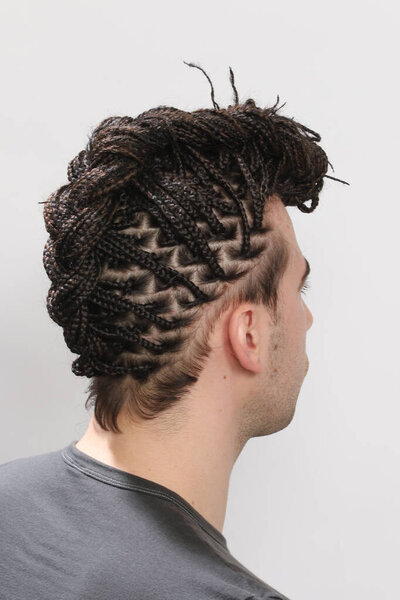 Stylish male model with afro braids posing in studio on isolated background. Style, trends, fashion concept.