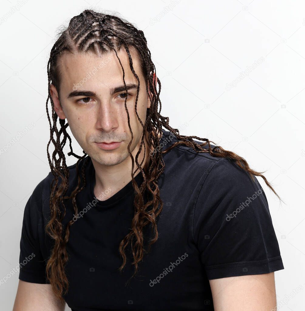 Attractive guy with braids posing in studio on isolated background. Style, trends, fashion concept.