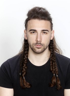 İzole edilmiş arka planda saç örgüleri olan şık bir erkek model. Tarz, saç stili, moda konsepti.