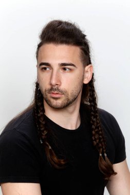 İzole edilmiş arka planda saç örgüleri olan şık bir erkek model. Tarz, saç stili, moda konsepti.