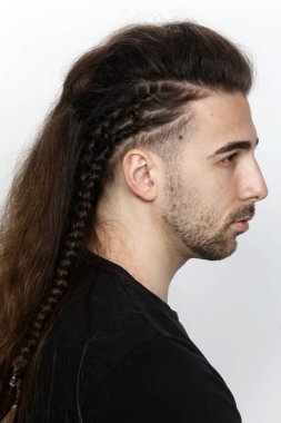 İzole edilmiş arka planda saç örgüleri olan şık bir erkek model. Tarz, saç stili, moda konsepti.