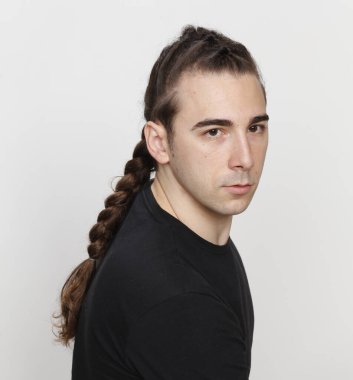 İzole edilmiş arka planda saç örgüleri olan şık bir erkek model. Tarz, saç stili, moda konsepti.